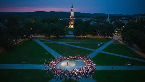 An aerial shot of a group gathered in a circle on the green in a candlelight vigil honoring the late Buddy Teevens.